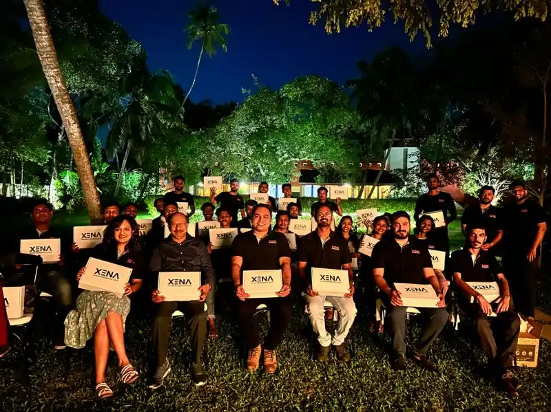 The Xena team posing outdoors at night, each holding a XENA sign